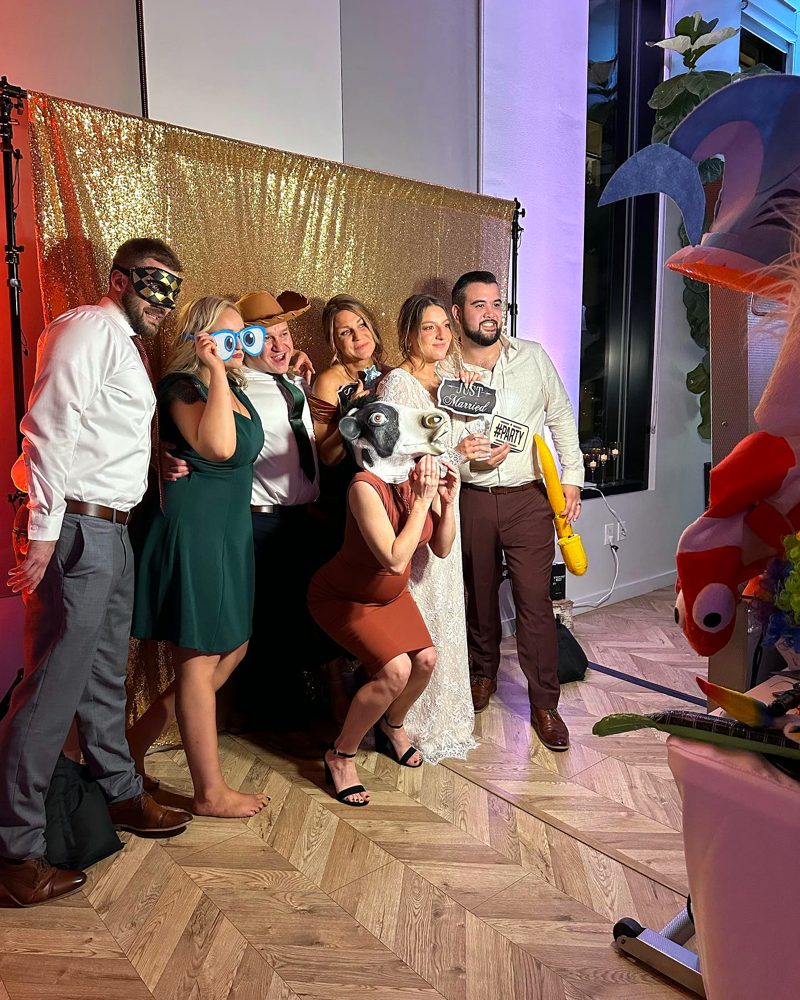 Wedding guests posing with props at the gold backdrop