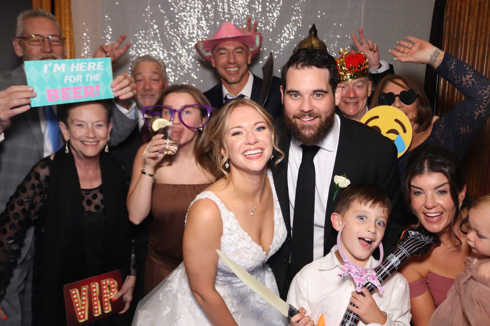 Bride, groom, and wedding guests with props in the photo booth